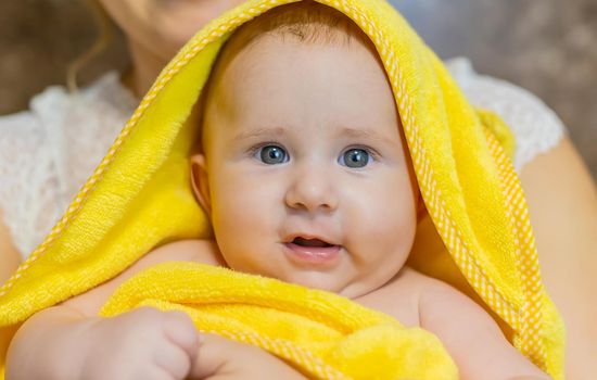 Baby after bathing in a towel. Selective focus. People.
