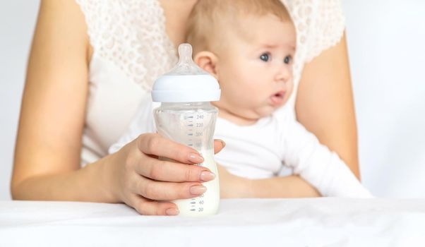 Mother feeds the baby from a bottle. Selective focus. People.
