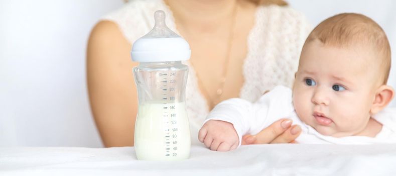 Mother feeds the baby from a bottle. Selective focus. People.