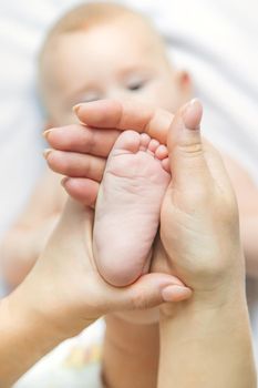 The mother keeps the baby's leg at home. Selective focus. People.