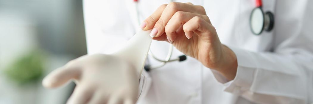 Close-up of doctor or nurse putting on sterile gloves before work in clinic. Medical worker in uniform, ready for appointment. Health, hospital concept