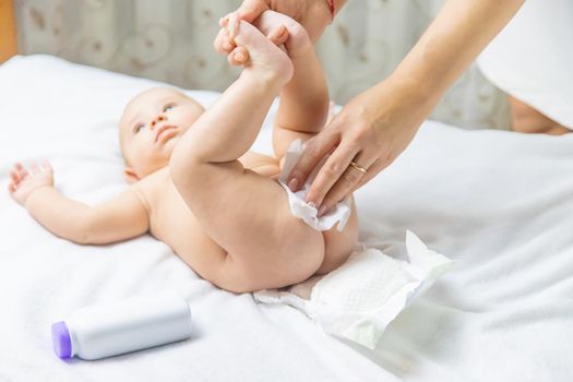 The mother changes the baby's diaper. Selective focus. People.