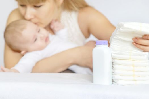 mother changes baby's diaper on a light background. Selective focus. people.