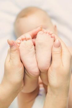 The mother keeps the baby's leg at home. Selective focus. People.