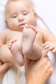 The mother keeps the baby's leg at home. Selective focus. People.