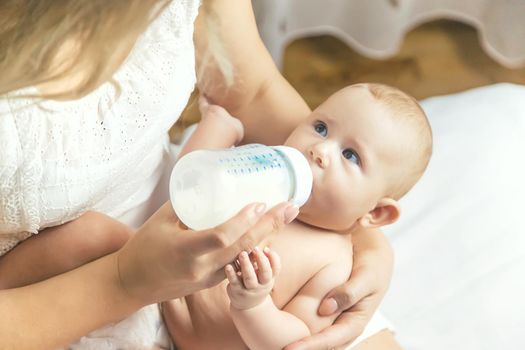 Mom feeds the baby with a bottle. Selective focus. People.
