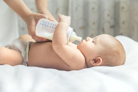 Mom feeds the baby with a bottle. Selective focus. People.