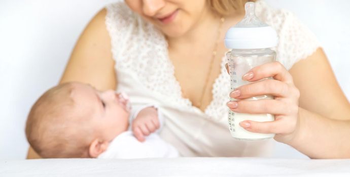 Mother feeds the baby from a bottle. Selective focus. People.