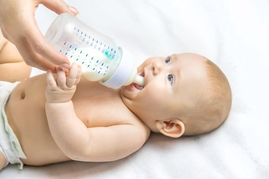 Mom feeds the baby with a bottle. Selective focus. People.