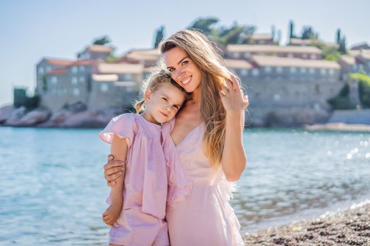 Mother and daughter tourists on background of beautiful view St. Stephen island, Sveti Stefan on the Budva Riviera, Budva, Montenegro. Travel to Montenegro concept.