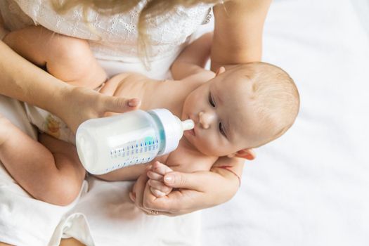 Mom feeds the baby with a bottle. Selective focus. People.