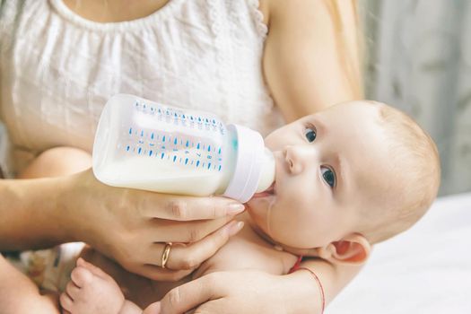 Mom feeds the baby with a bottle. Selective focus. People.