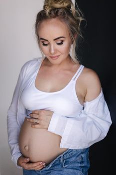 Portrait of pregnant woman in studio. Denim style.