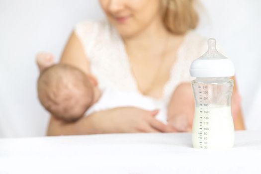 Mother feeds the baby from a bottle. Selective focus. People.