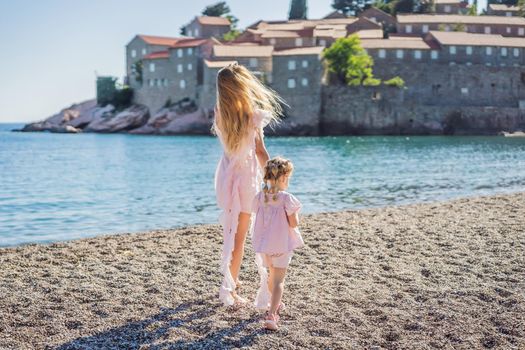 Mother and daughter tourists on background of beautiful view St. Stephen island, Sveti Stefan on the Budva Riviera, Budva, Montenegro. Travel to Montenegro concept.