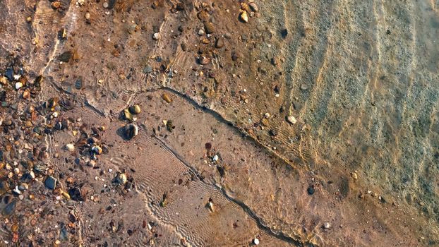 Top view on colorful pebbles covered by water. Close up view of smooth round pebble stones on the beach.