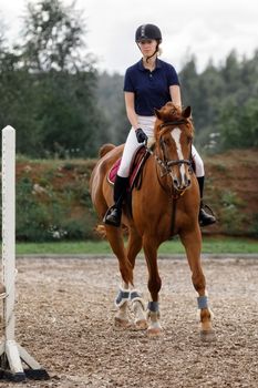 A girl in the form of a jockey rides a horse at the hippodrome. Horseback riding lessons, horseback riding.