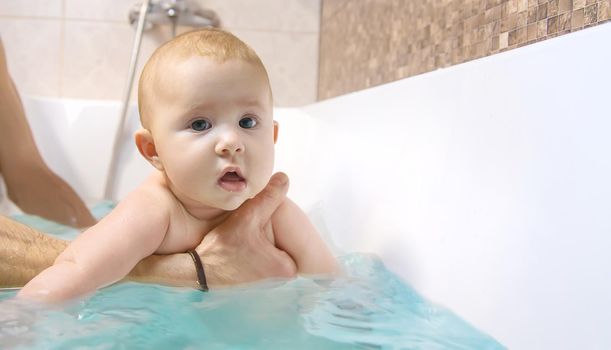The father bathes the little baby. Selective focus. Copy space.