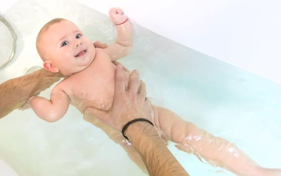 The father bathes the little baby. Selective focus. Copy space.