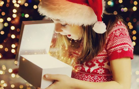 Child opens gifts under the Christmas tree. Selective focus. Holiday.