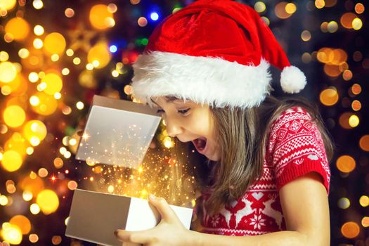 Child opens gifts under the Christmas tree. Selective focus. Holiday.