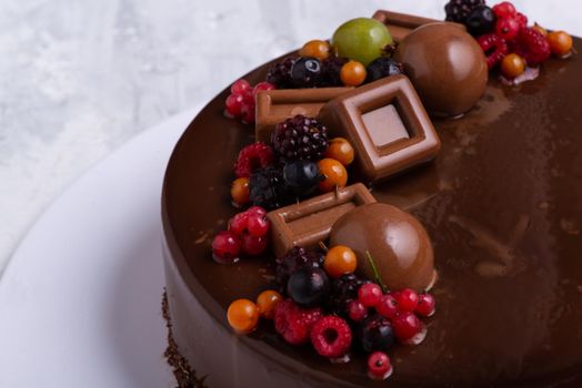 A close-up shot of a chocolate glaze cake decorated with berries.