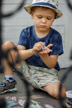 A little boy in a blue shirt tries to draw with colored crayons on his hands. The child learns and experiments.