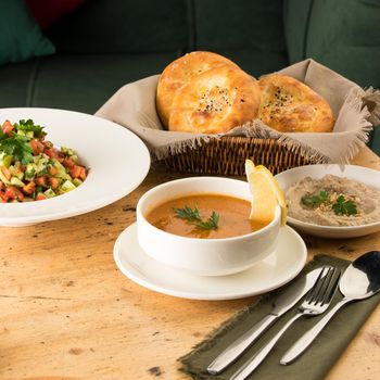 A closeup shot of a soup and appetizers near basket of breads