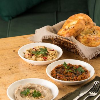 Mediterranean dishes, baba ganoush, muhammara and hummus with a basket of bread