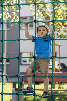 Child at playground. Little boy on a playground climbing net tower. Outdoor play space on Polyester Twisted Rope. Playground Climbing Rope Tower