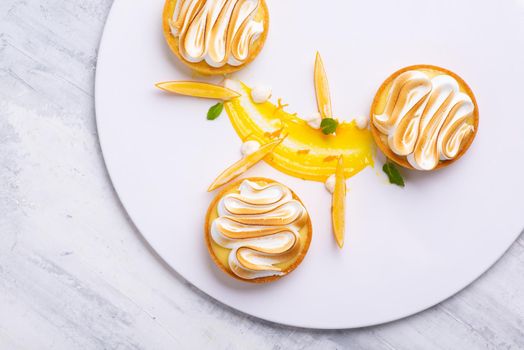 The appetizing lemon tartlets with meringue served on a white plate