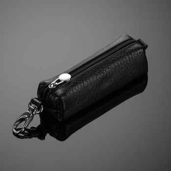 A closeup of a leather key case on a grey background