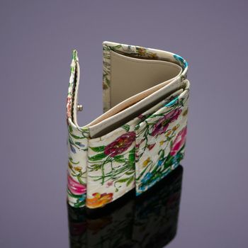 A close-up shot of a floral money purse placed on a reflecting surface.