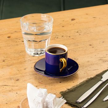 A cup of coffee near glass of water and baklava