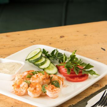 A dinner table with meals with hummus, shrimp, vegetables and beef