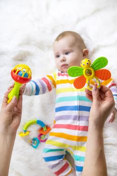 The mother gives a rattle to the baby. Selective focus. child.