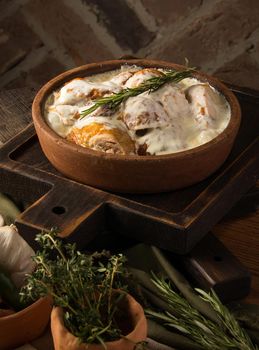 A vertical shot of a chicken covered in a creamy sauce