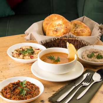 A closeup shot of a soup and appetizers near basket of breads