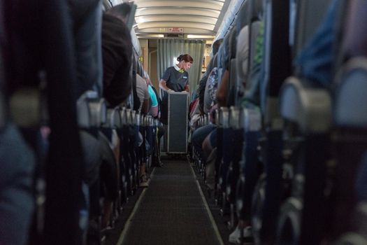 An angle shot of a stewardess passing something to passengers.