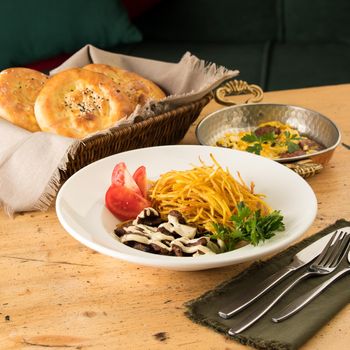 A closeup of a delicious dish with shredded potatoes, beef, sauce and sandwiches