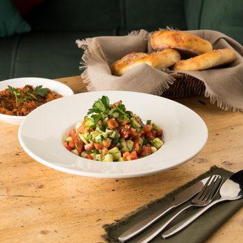 A close up shot of salads and appetizers near basket of breads