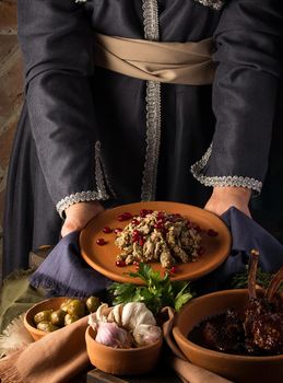 A vertical shot of a waitress presenting a kuchmachi and tomahawk steak in the background