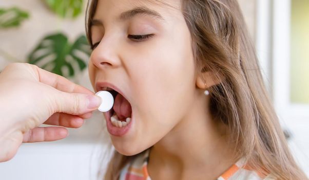 mother giving vitamin c pill to her child. dietary supplements for kids. Selective focus. People.