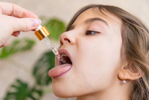 mother giving vitamin drops with dropper to her child. dietary supplements for kids. Selective focus.