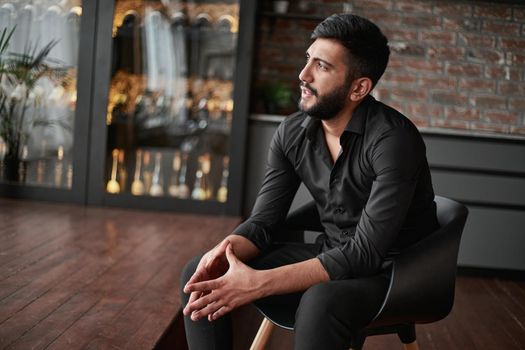 portrait of a business owner sitting in his wine shop.