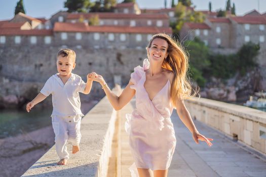 Mother and son tourists on background of beautiful view St. Stephen island, Sveti Stefan on the Budva Riviera, Budva, Montenegro. Travel to Montenegro concept.