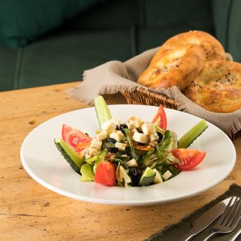 A close up shot of a salad and appetizers near basket of breads