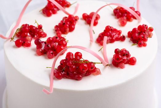 A top view shot of a white cake designed by red berry on a white plate