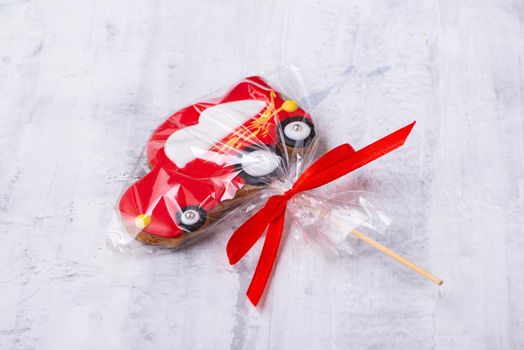 A closeup shot of a red car-shaped cookie on a stick