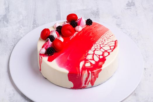 An angle shot of a mirror glaze cake decorated with berries.